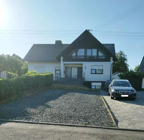 Wohnhaus der Ferienwohnung Jessica mit Holzbalkon im Giebel und Kieseinfahrt davor
